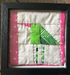 Framed quilted green bird wall art with lime green and pink fabric on white background in black frame