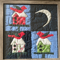 Framed four-panel Christmas birdhouse quilted wall art with red, green and white snowflake fabric on starry night background
