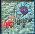 Framed quilted wall art with orange bird looking up at bold blue daisy flower on sage green floral background in dark blue frame