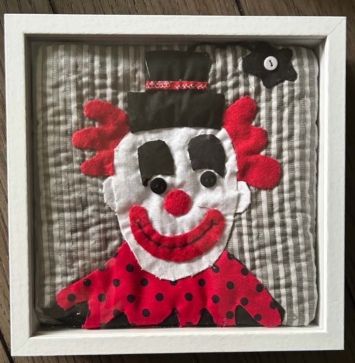 Bold quilted clown portrait appliqué wall art with red hair and top hat in white shadow box frame